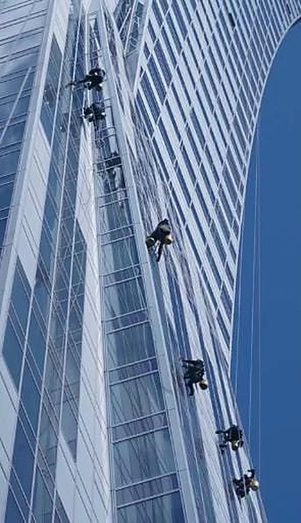 Zespół alpinistów myjący fasadę wieżowca Warsaw Spire w Warszawie